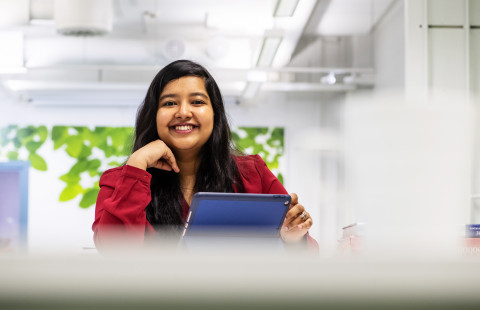 Young woman smiling, laptop in front of her.